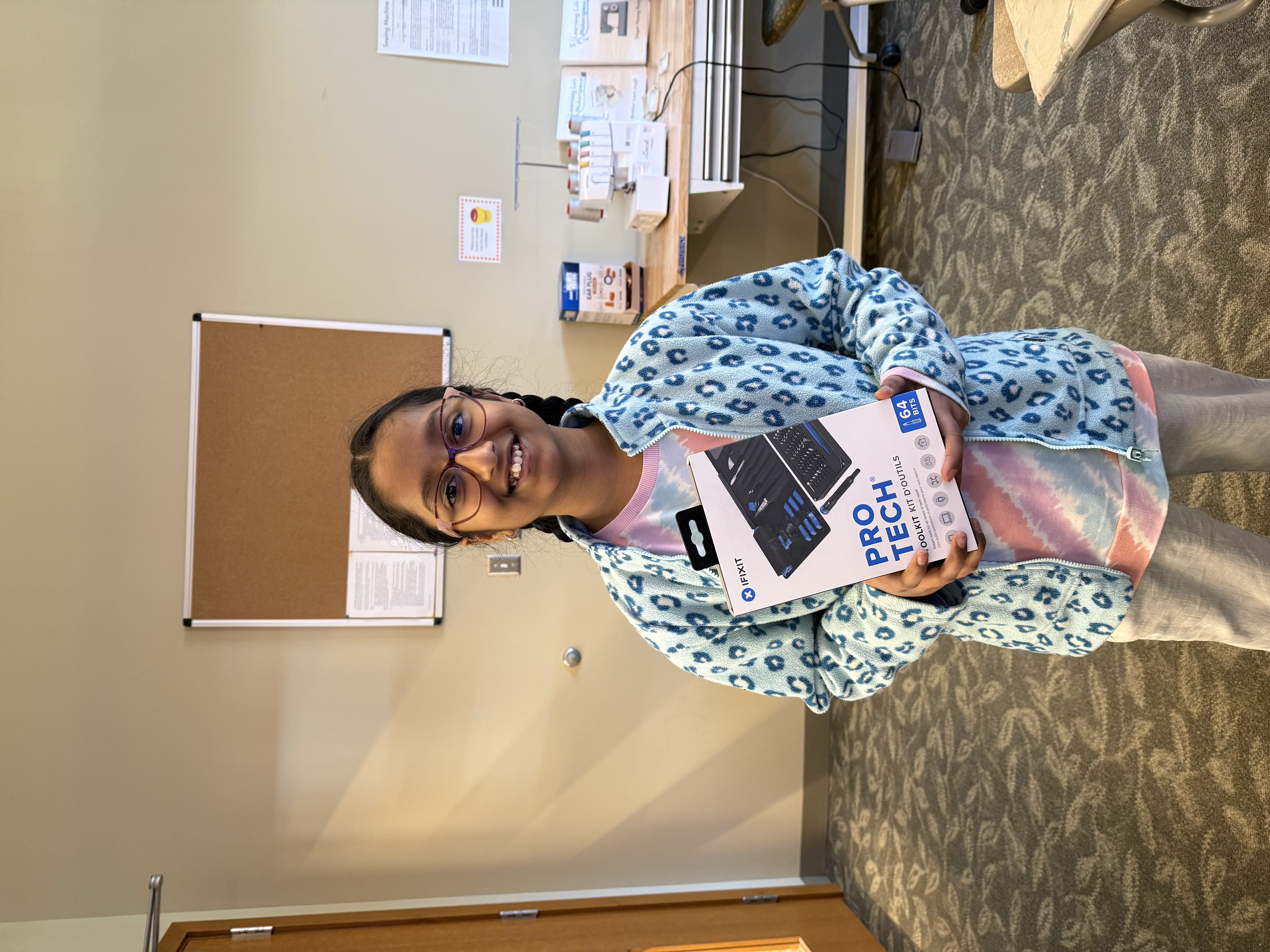 A young attendee smiling while holding a new iFixit Pro Tech toolkit